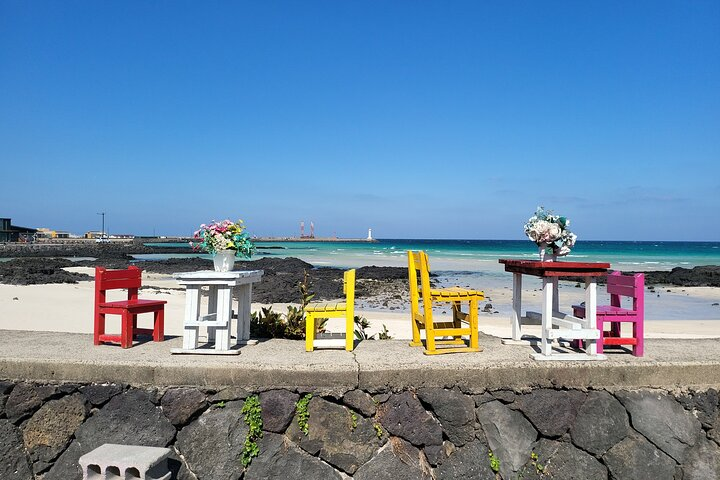 Brightly colored chairs line a beachside setting inviting moments of relaxation and stunning ocean views. Experience the serene beauty of Jeju Island while enjoying a peaceful retreat with nature.